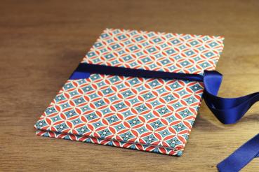 small photo album with geometric pattern in red, blue, white, blue satin bow